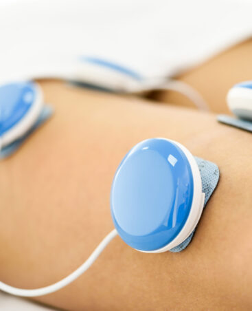 Electro stimulation in physical therapy to a young woman. Medical check at the leg in a physiotherapy center.